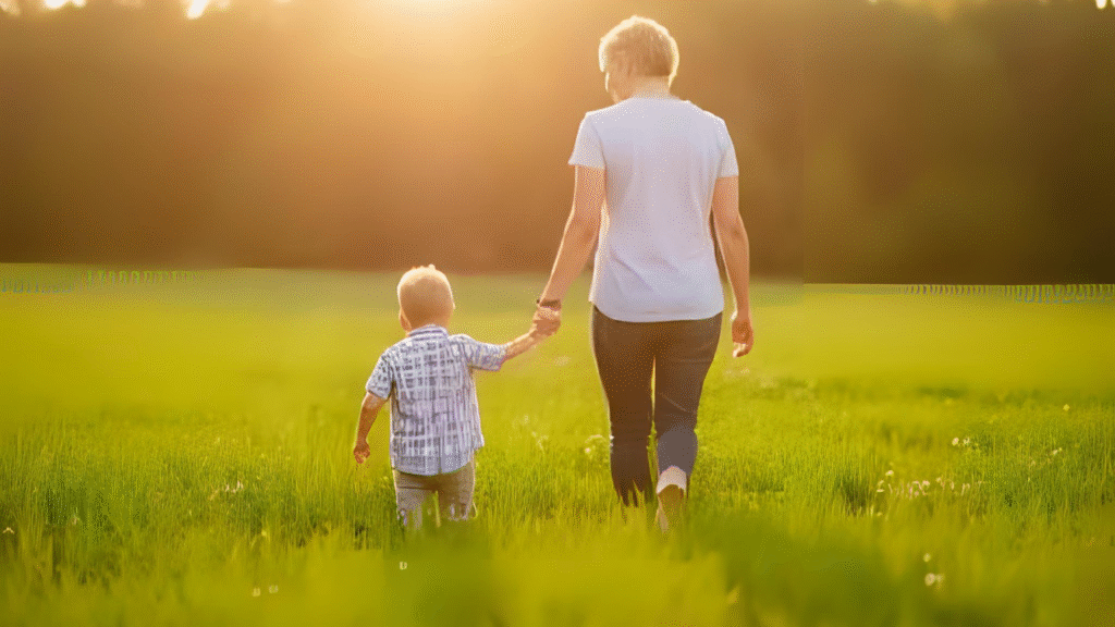 Mãe segurando a mão do filho em campo verde iluminado pelo sol.
